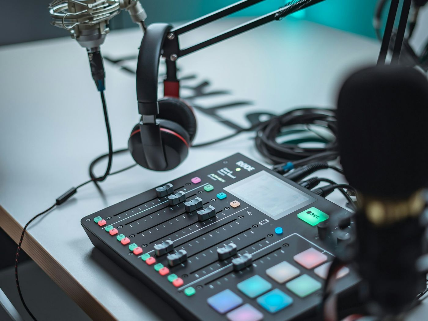 A podcast mixing desk with a microphone on a boom arm and headphones